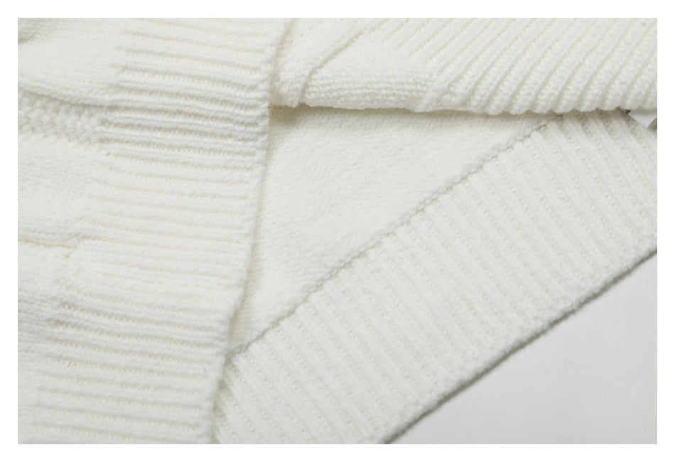 Close-up of an ivory knit garment showing ribbed sections and a stitched seam.