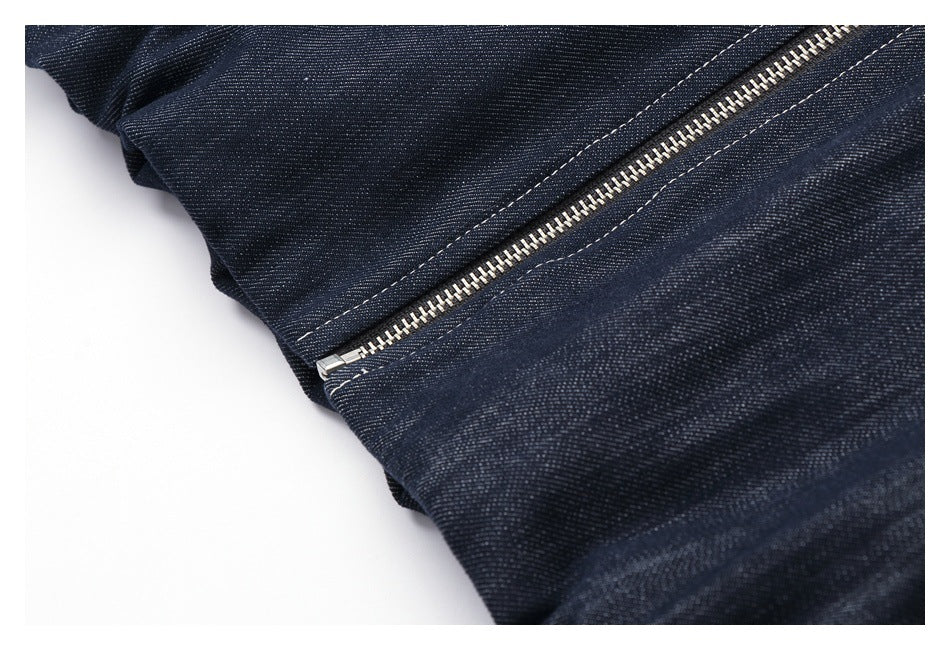 Close-up of a silver zipper set into dark indigo denim with contrasting stitching.