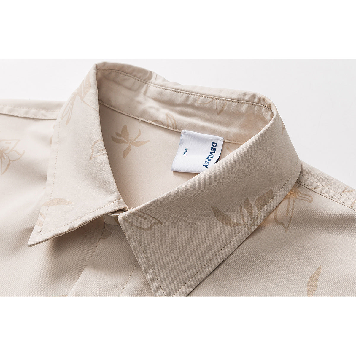 Close-up of a beige floral shirt collar with a white sewn-in label.