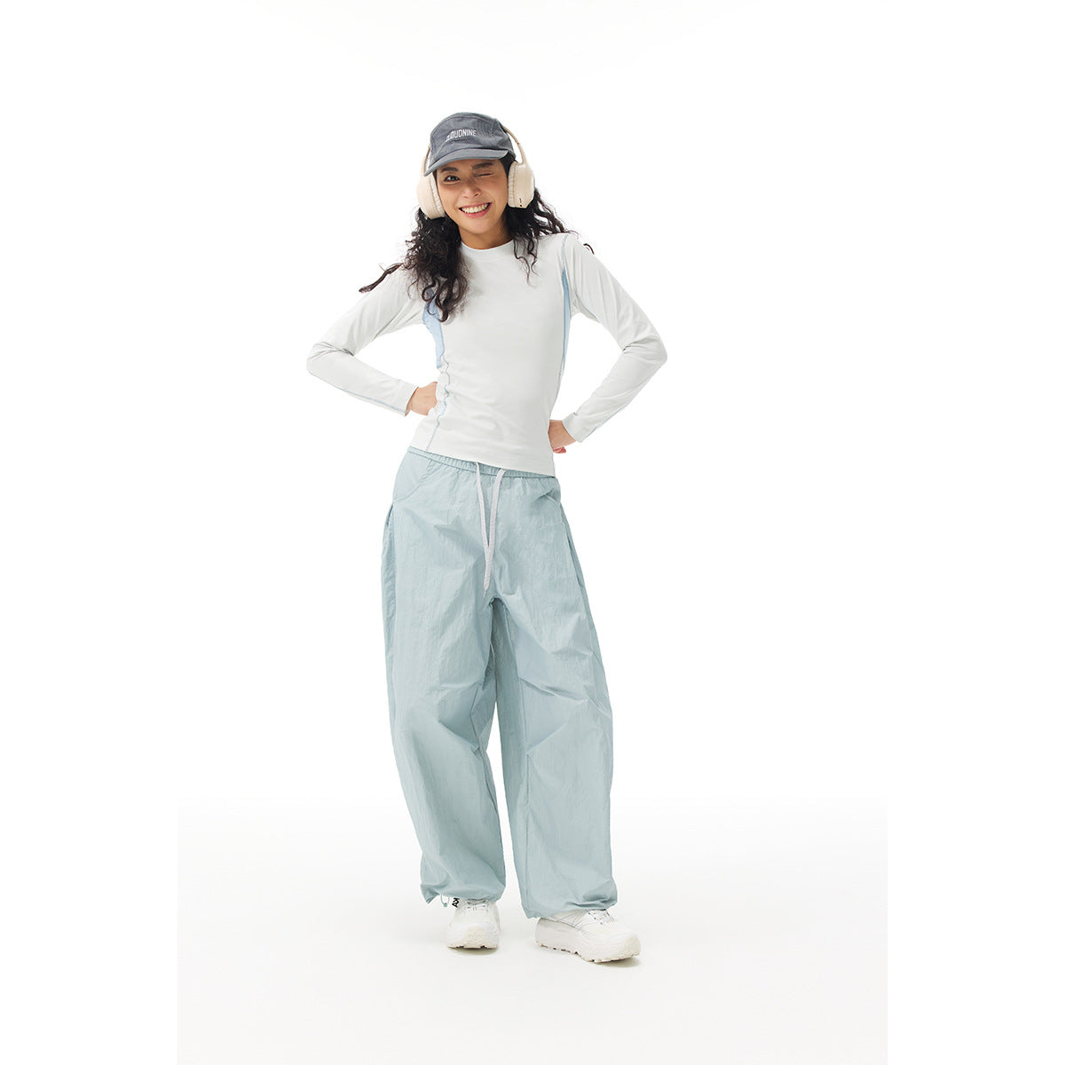 Model wearing a white long-sleeve top with pale blue panels and loose pale blue pants.
