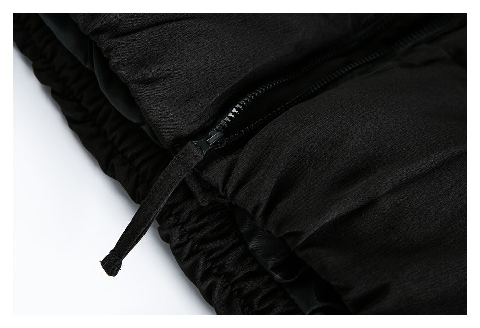 Close-up of a black garment zipper, pull tab, and gathered edge.