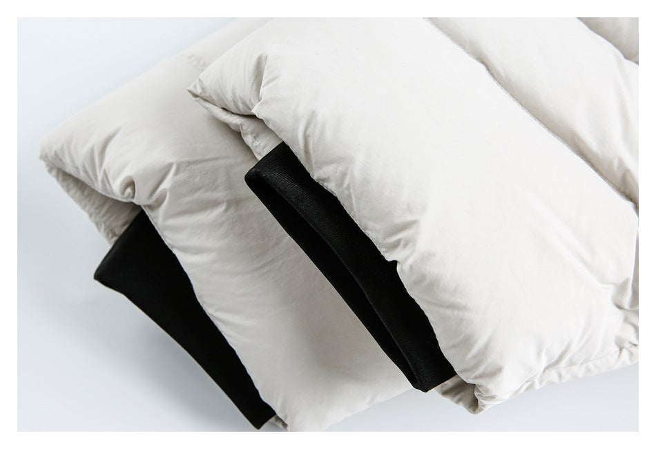 Close-up of a white padded jacket with black fabric tabs visible between the quilted layers.