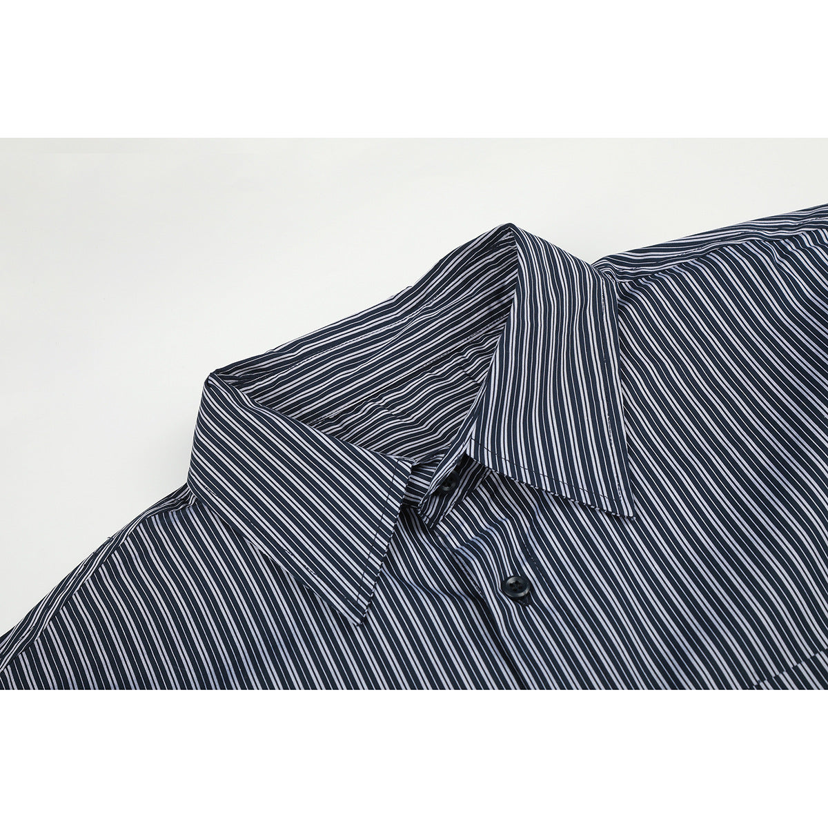 Close-up of a dark shirt with thin white stripes, showing its pointed collar and upper buttons.