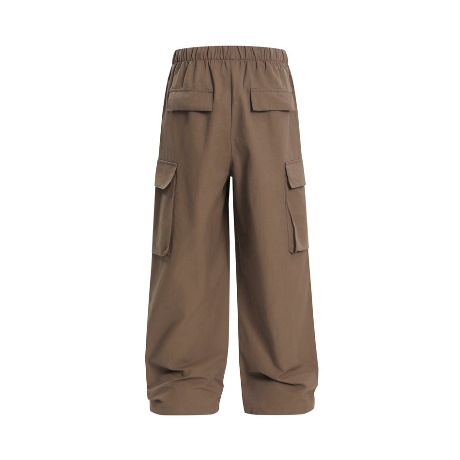 Back view of loose brown cargo pants with an elastic waist, two rear flap pockets, and large side cargo pockets.