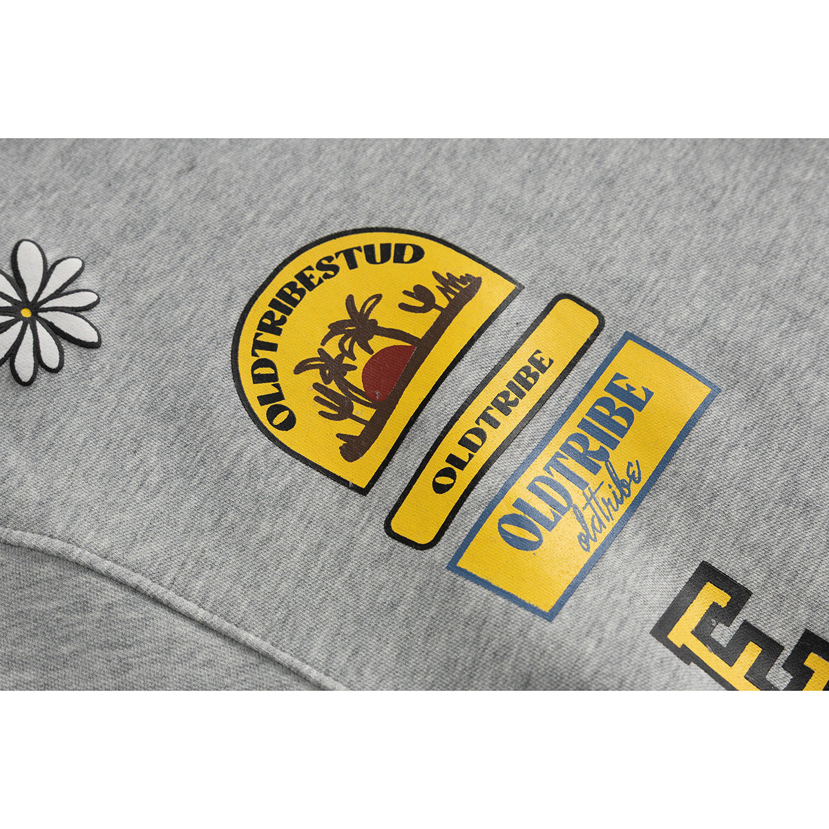 Close-up of yellow and black graphic prints and a daisy on a heather gray pullover.