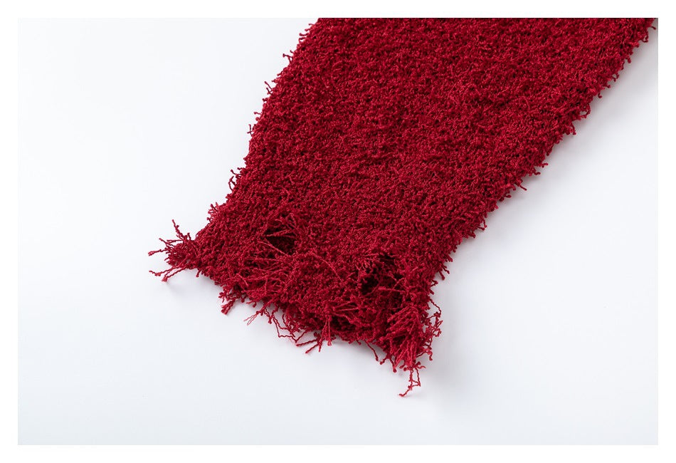 Close-up of deep red fuzzy knit fabric with a loose, fringed edge against a white background.