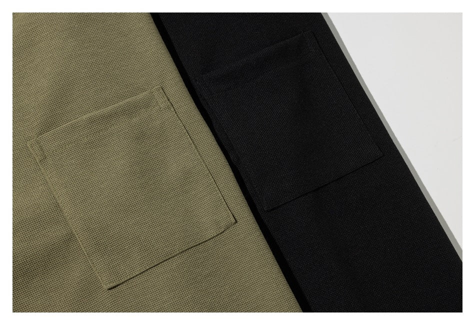 Close-up of square patch pockets on olive-khaki and black garments.