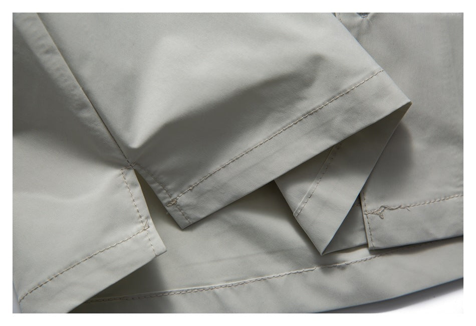 Overlapping stitched edges and folded hems on pale gray shirt fabric.