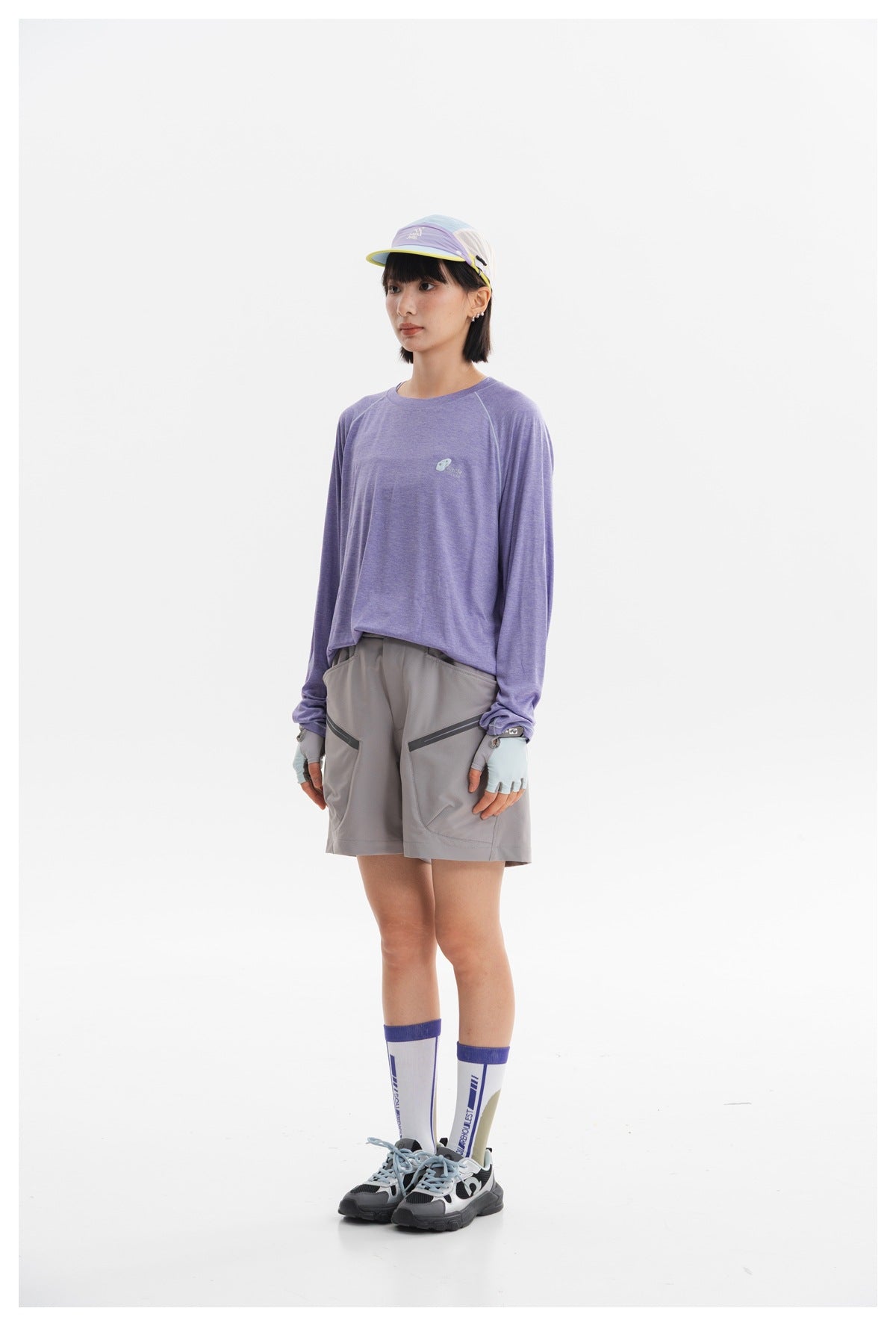 Model wearing a lavender long-sleeve shirt, gray shorts, cap, gloves, and tall socks.