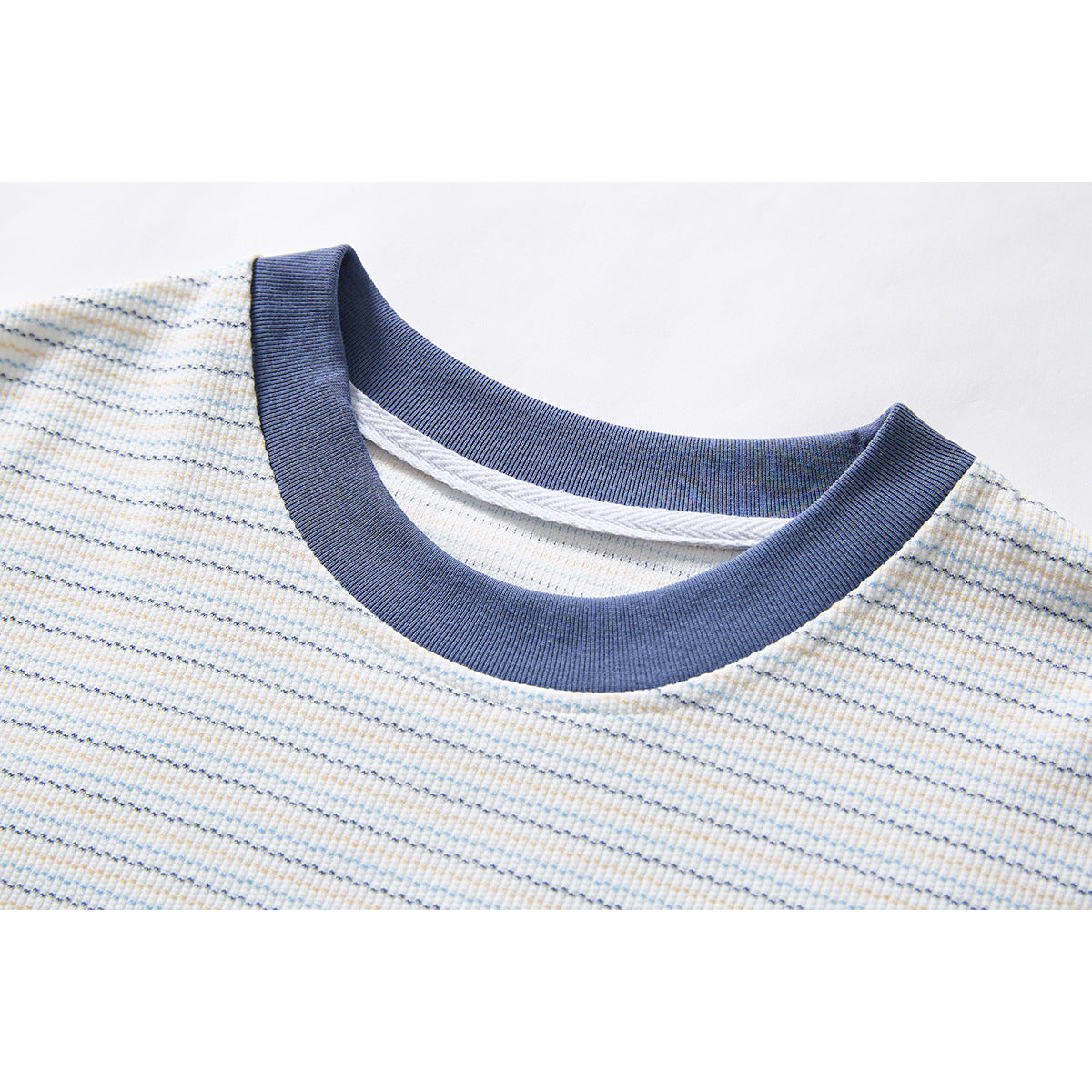 Close-up of a white T-shirt with fine blue and tan stripes and a wide navy ribbed crew neck.