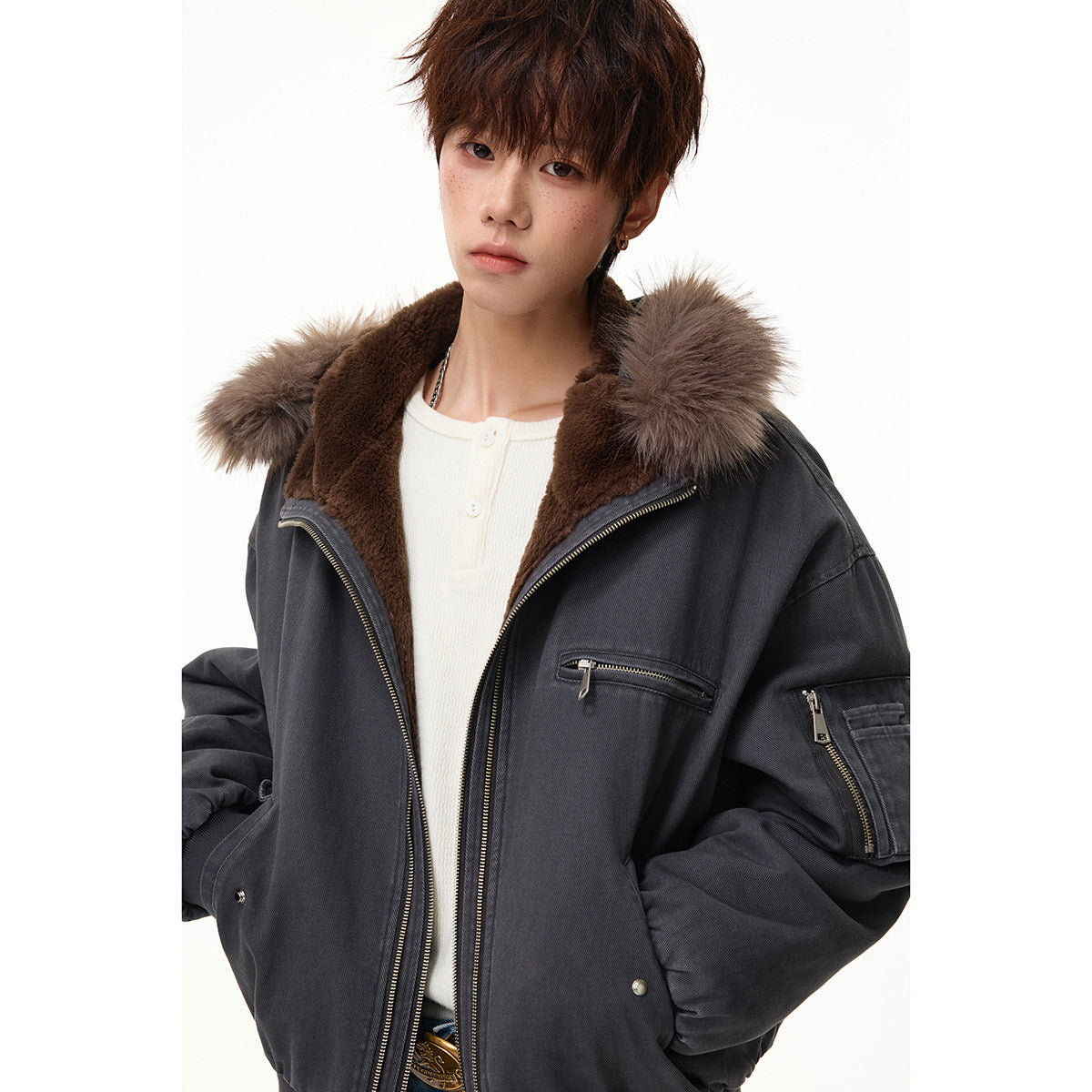 Close view of a model wearing an open charcoal bomber jacket with brown lining and a taupe fur-trimmed hood.