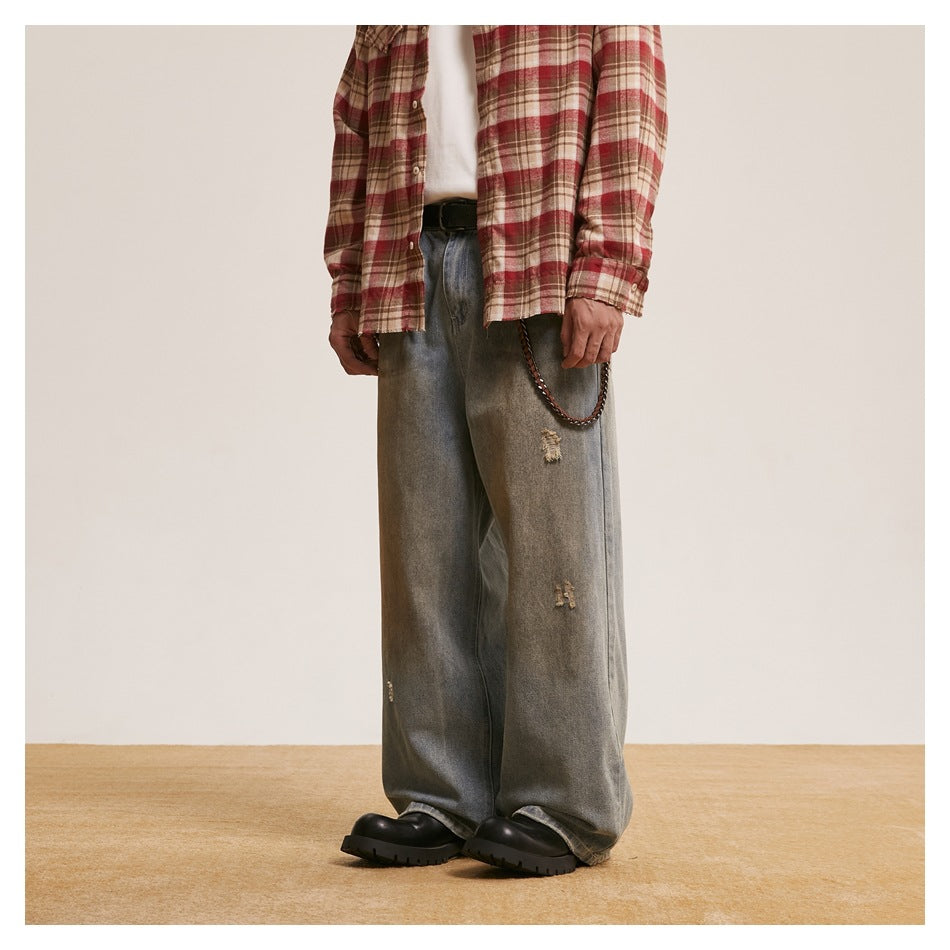 Model in wide-leg faded blue jeans with a red plaid shirt, chain and black boots, angled side view