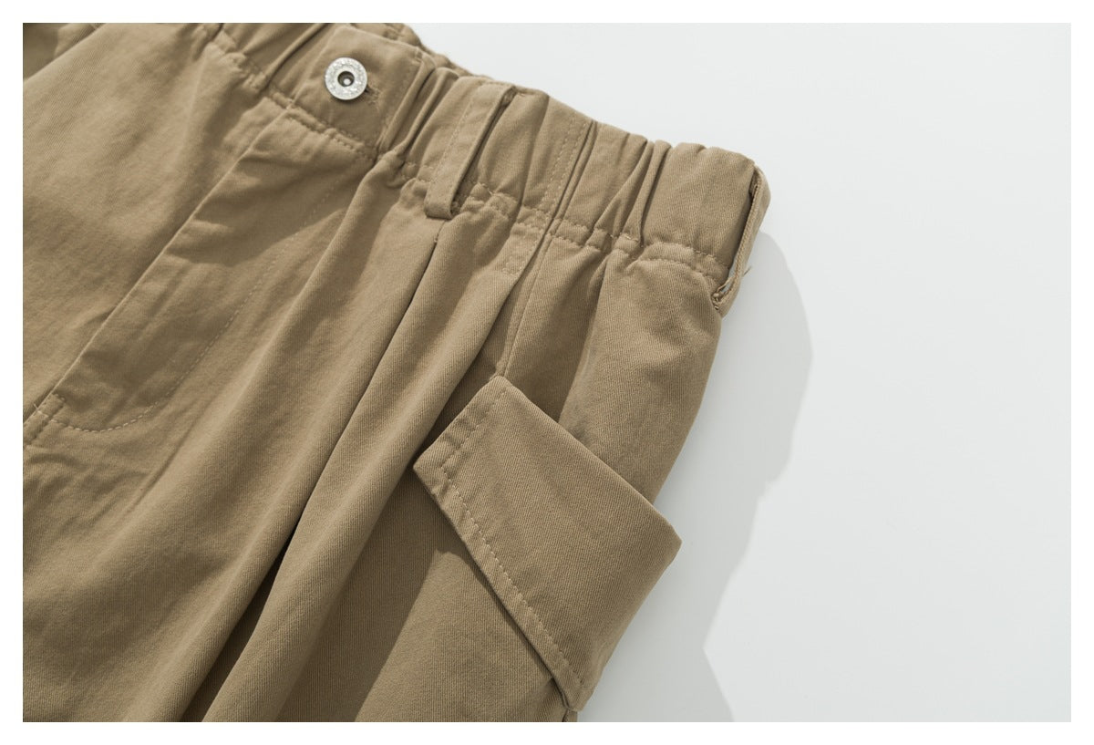 Close-up of khaki cargo pants showing the elastic waistband, button, belt loop and side flap pocket.