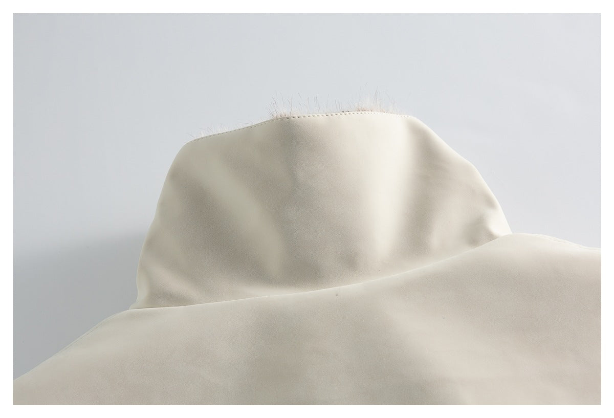 Close-up of the ivory coat's raised collar, with a few pale fur fibers visible along its edge.
