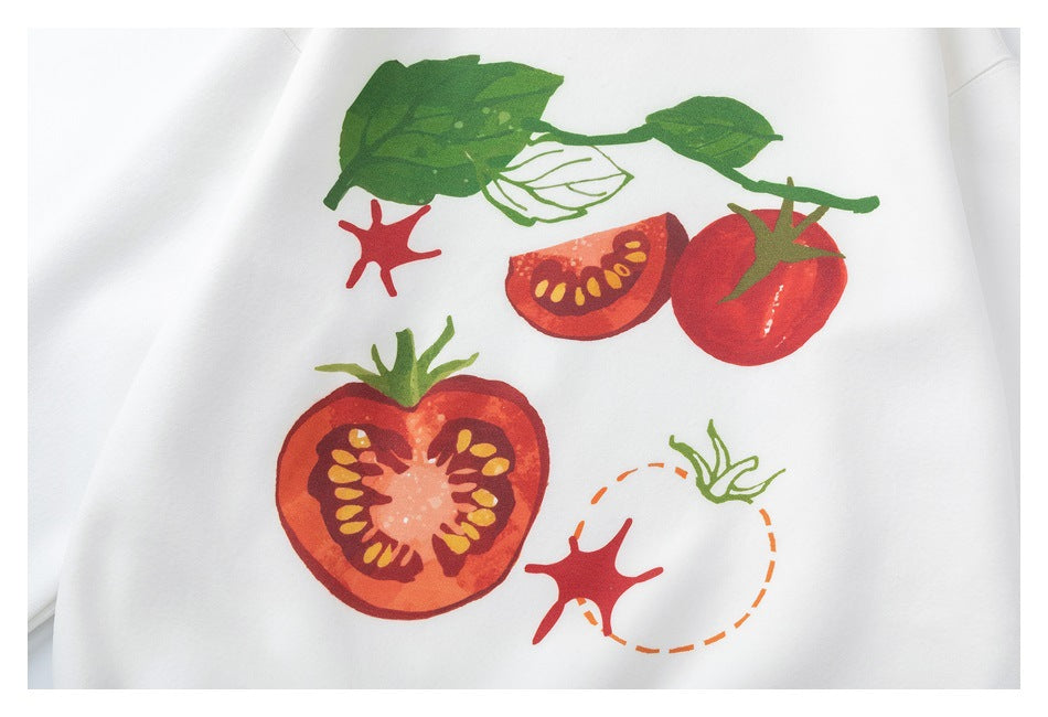 White garment detail showing a colorful print of tomatoes and green leaves.