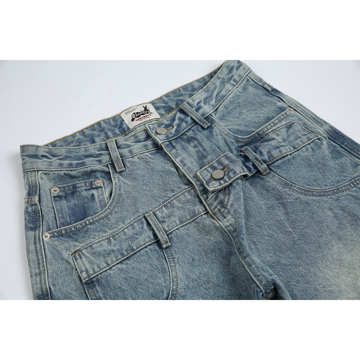 Close-up of light blue washed jeans showing the front waistband, button fly, belt loops, and pockets.