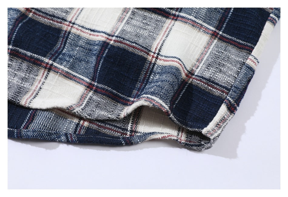 Close-up of the hem and side seam of a navy, white, gray, and red plaid shirt.