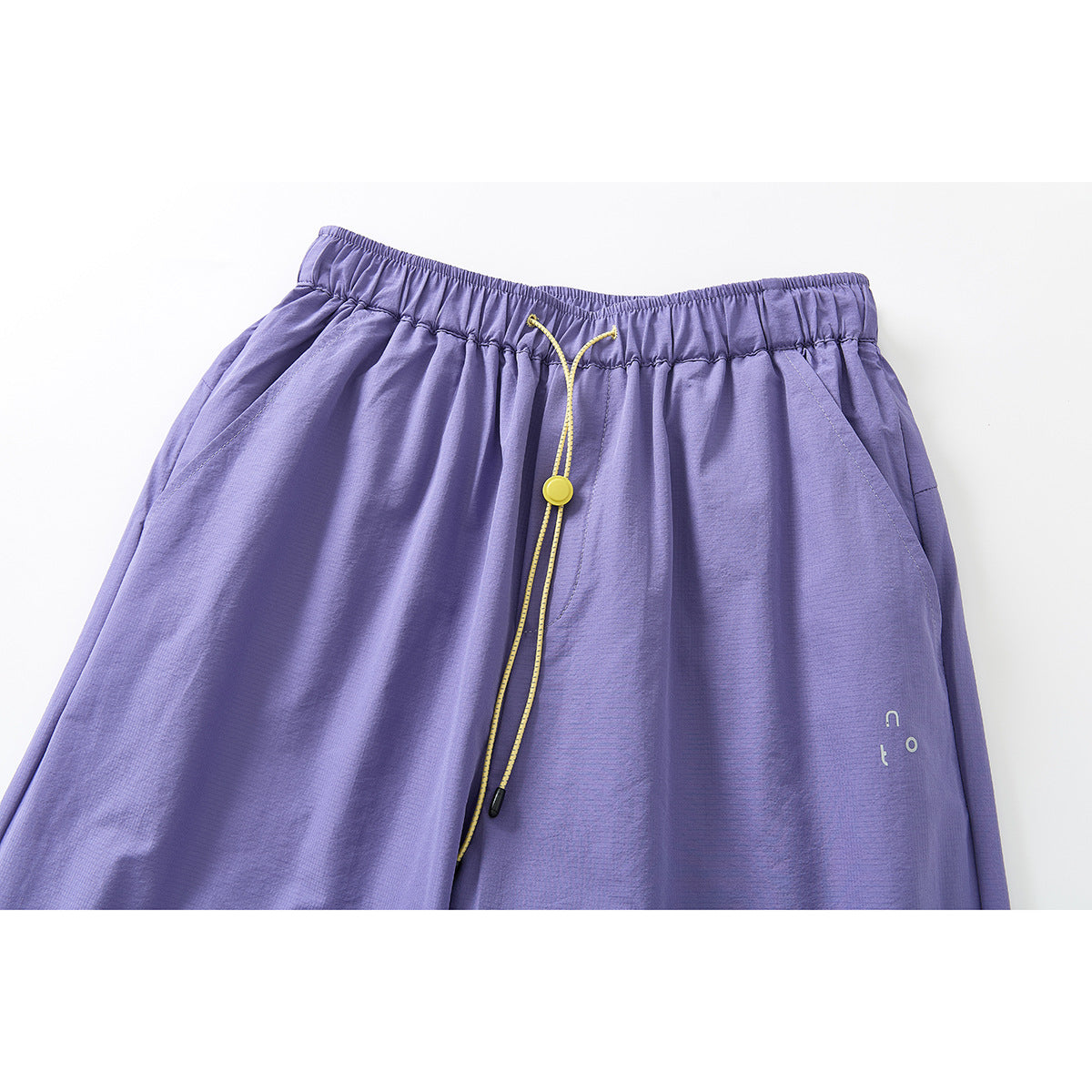 Close-up of lavender wide-leg pants with an elastic waist, yellow drawcord and side pockets.