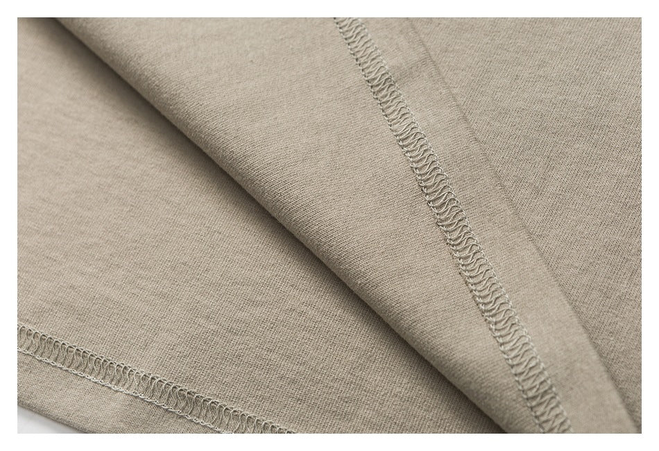 Close-up of taupe garment fabric showing interior overlock stitching along folded seams.