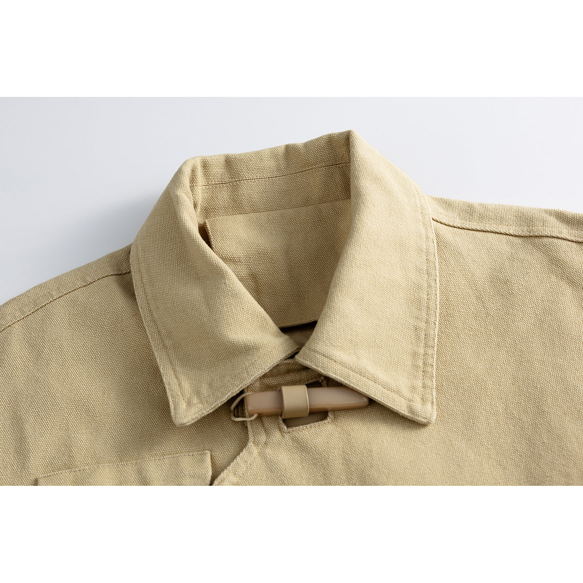 Close-up of a sand-colored jacket collar with a tan toggle closure.