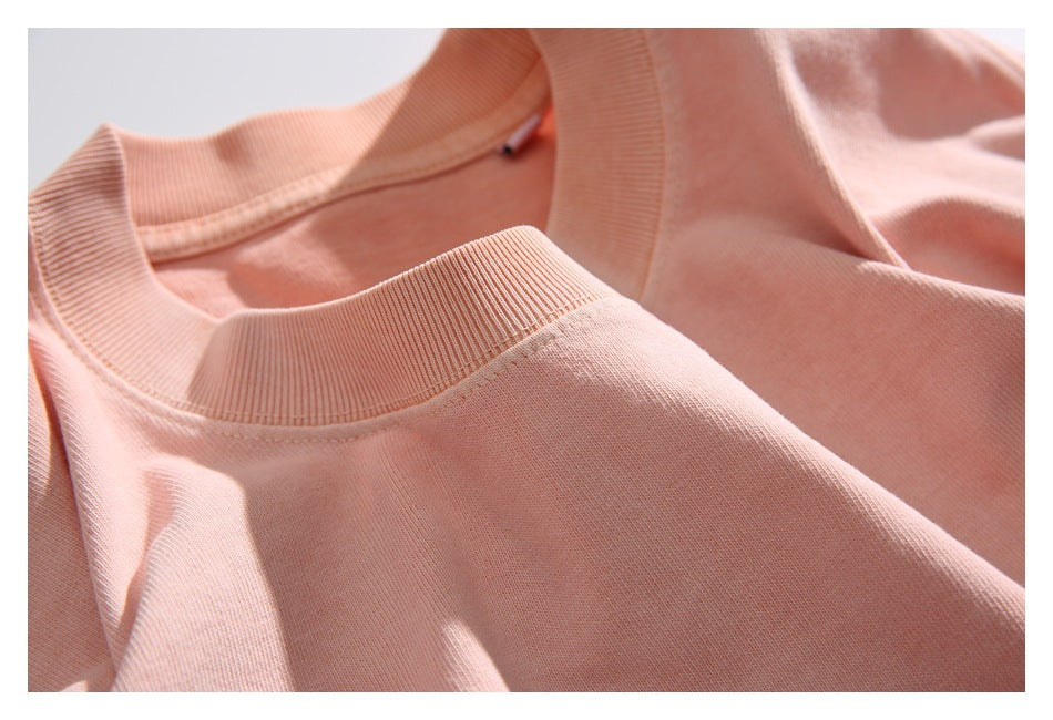Close-up of the peach T-shirt's ribbed crew neckline and shoulder seams.