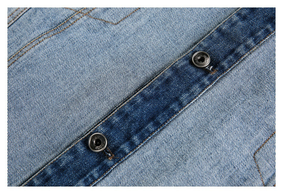 Close-up of a dark blue denim button placket with two metal buttons against faded blue denim.