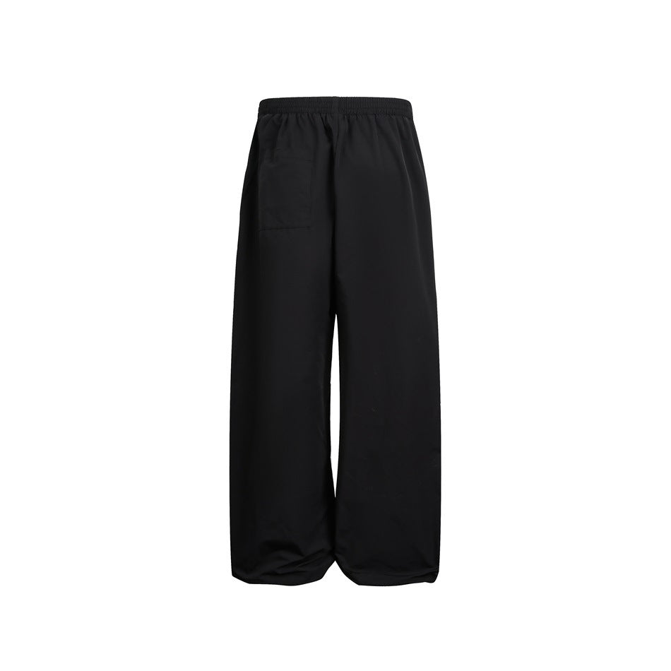 Back view of black wide-leg pants with an elastic waist and a rectangular patch pocket.