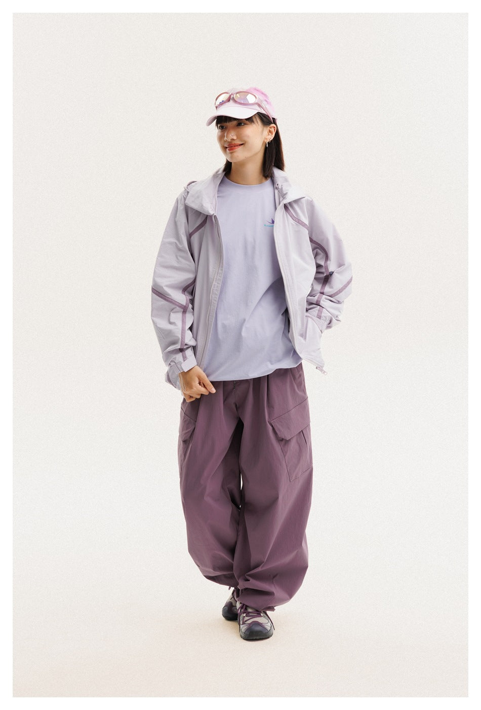Woman wearing an open light lavender jacket over a pale shirt with plum cargo pants.