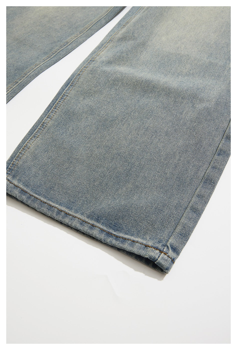 Close-up of the light blue jeans leg and hem, showing faded denim and contrast stitching.