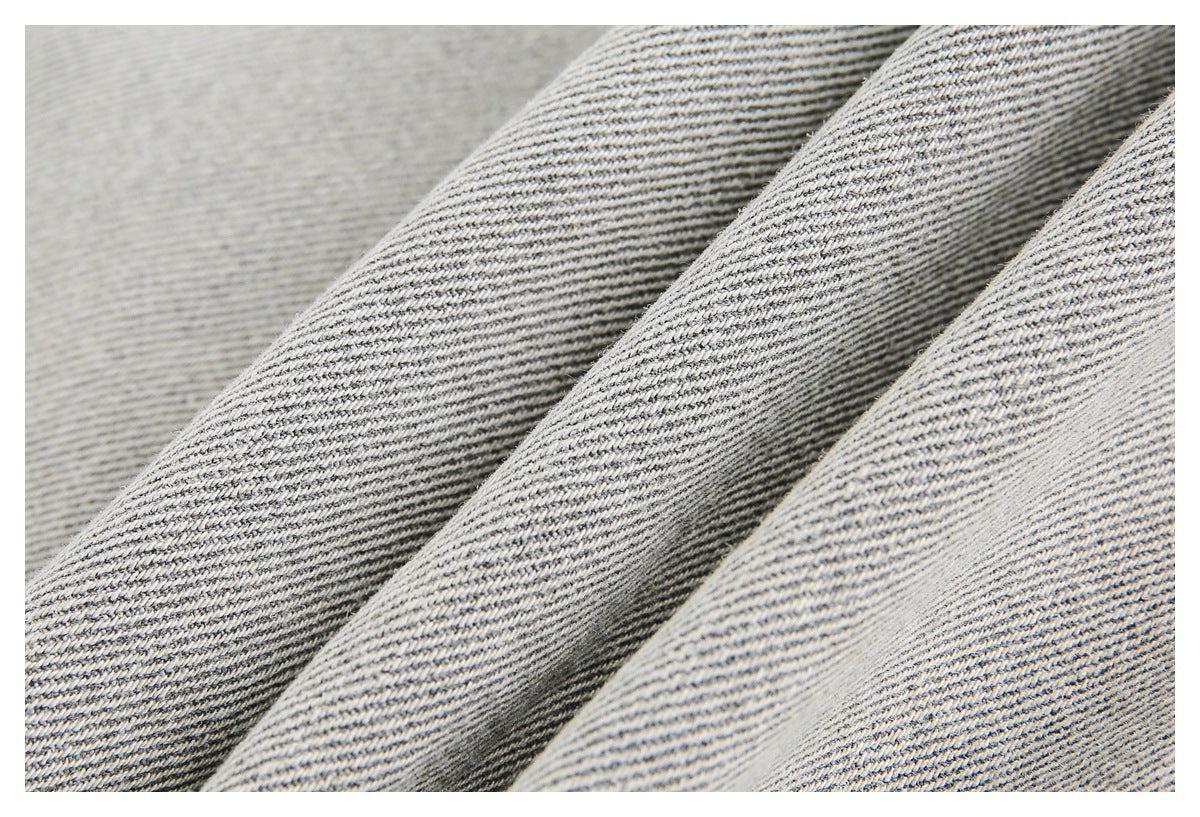 Extreme close-up showing the light gray jacket’s diagonal woven surface and folds.