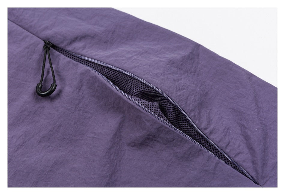 Close-up of purple pants showing a diagonal zippered mesh vent and black cord pull.