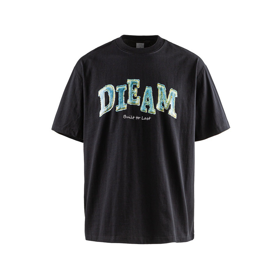 Black short-sleeve crew-neck T-shirt with blue-and-yellow “DREAM” lettering and “Built to Last” on the chest.