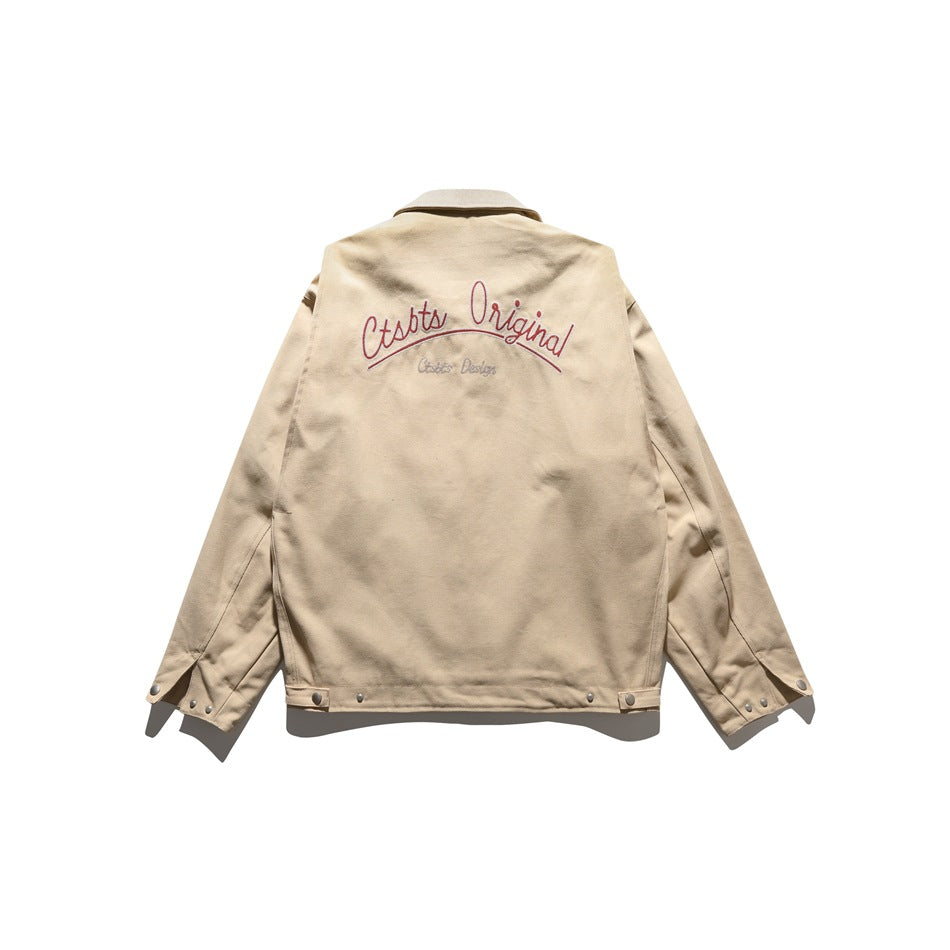 Back view of a beige jacket with red and gray script embroidery across the upper back.