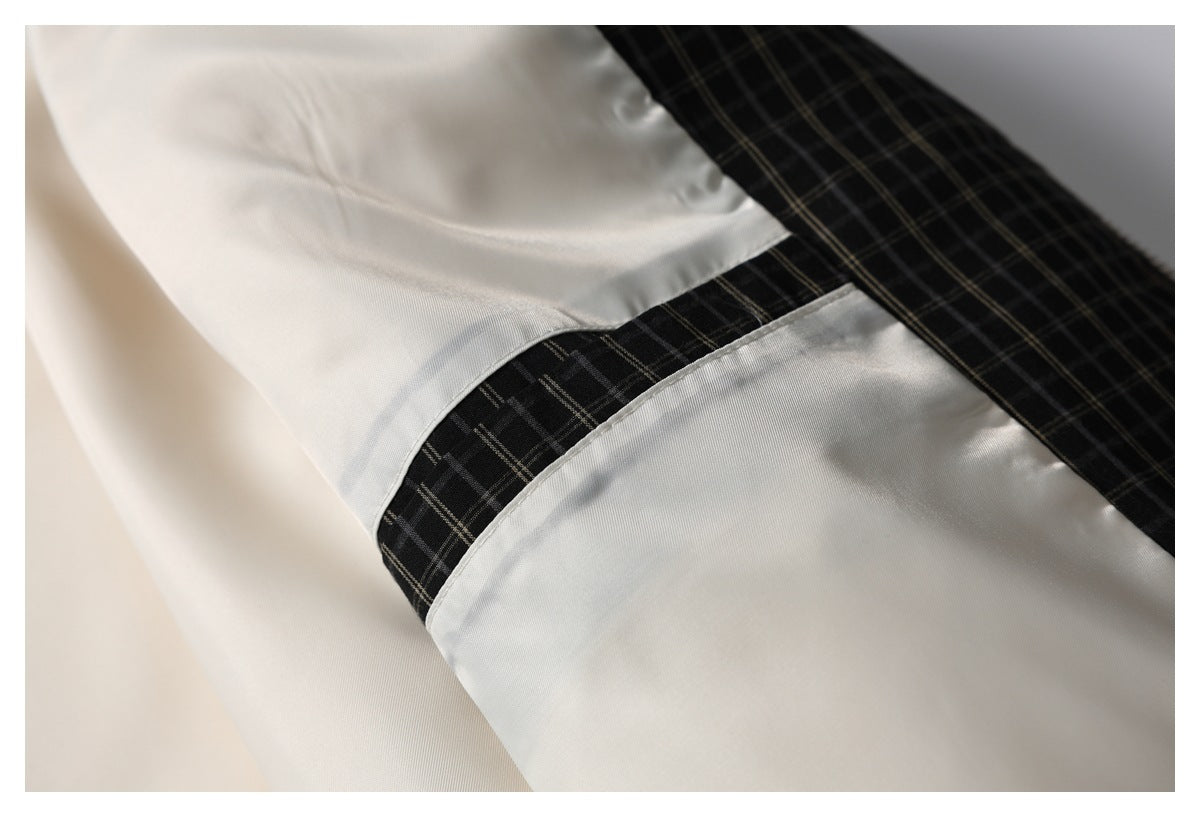 Close-up of the ivory jacket's interior, showing a black plaid panel and pale fabric seam.