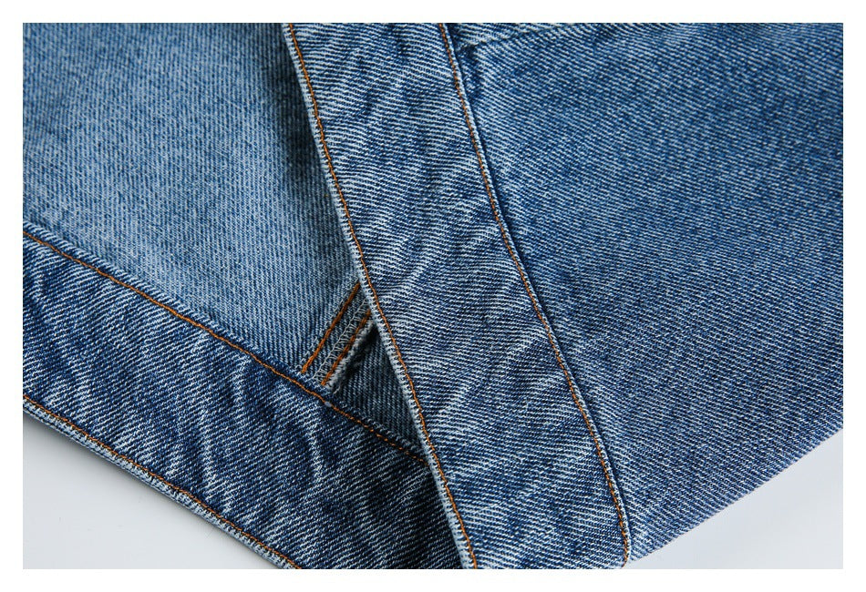 Close-up of intersecting blue denim panels with orange topstitched seams.
