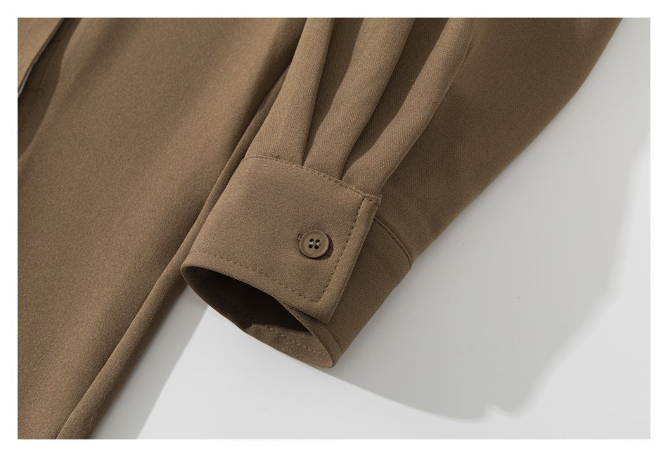 Close-up of a brown sleeve cuff with pleats and a small button.