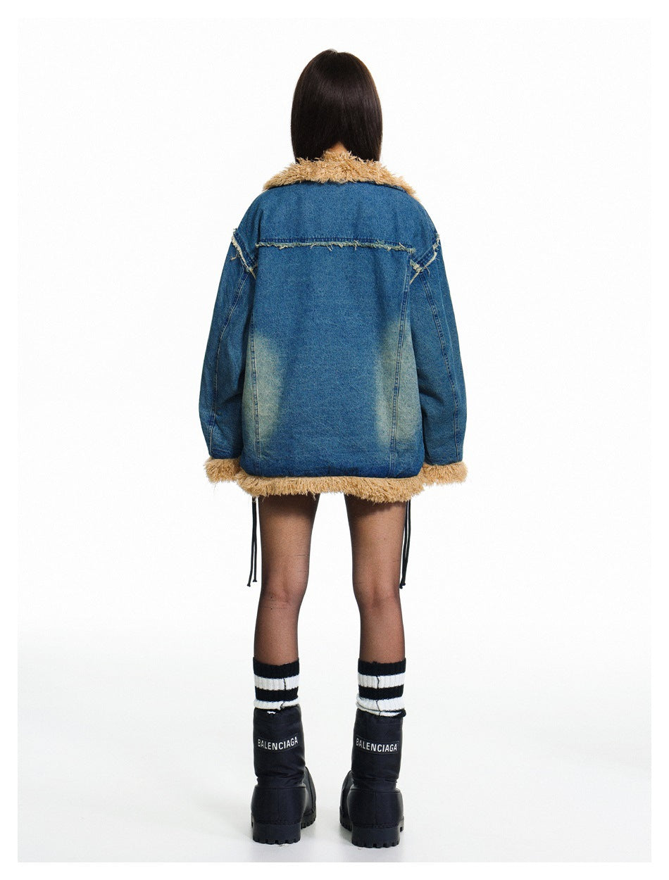 Rear view of a model wearing an oversized blue denim jacket with tan shaggy trim at the collar, cuffs, and hem.