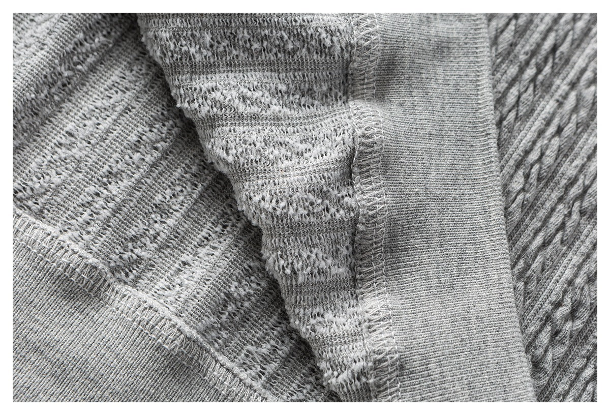 Close-up of the inside of gray knit fabric, showing seam stitching and a ribbed edge.