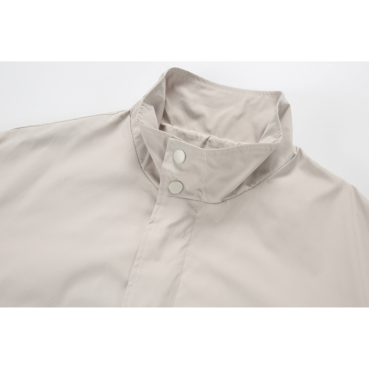 Close-up of a light beige jacket's stand collar and snap-button front placket.