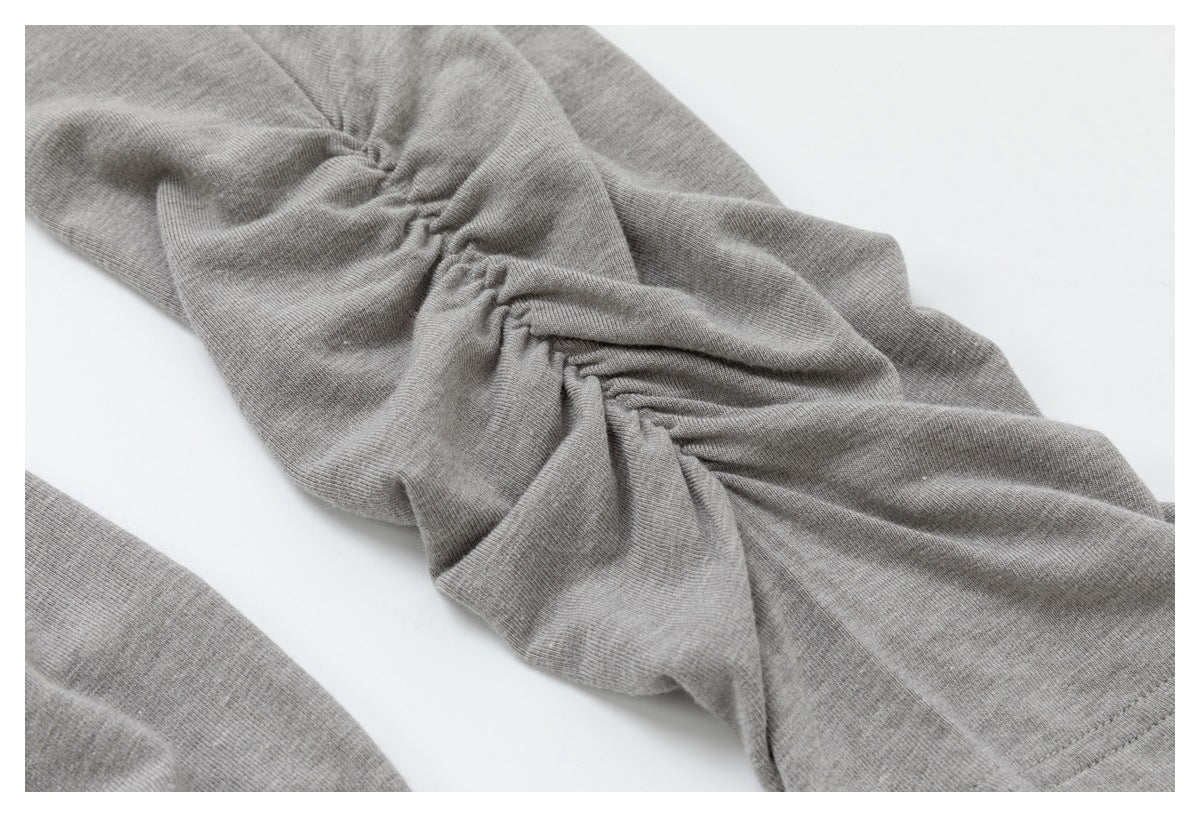 Close-up of gray knit garment fabric with a gathered, ruched seam.