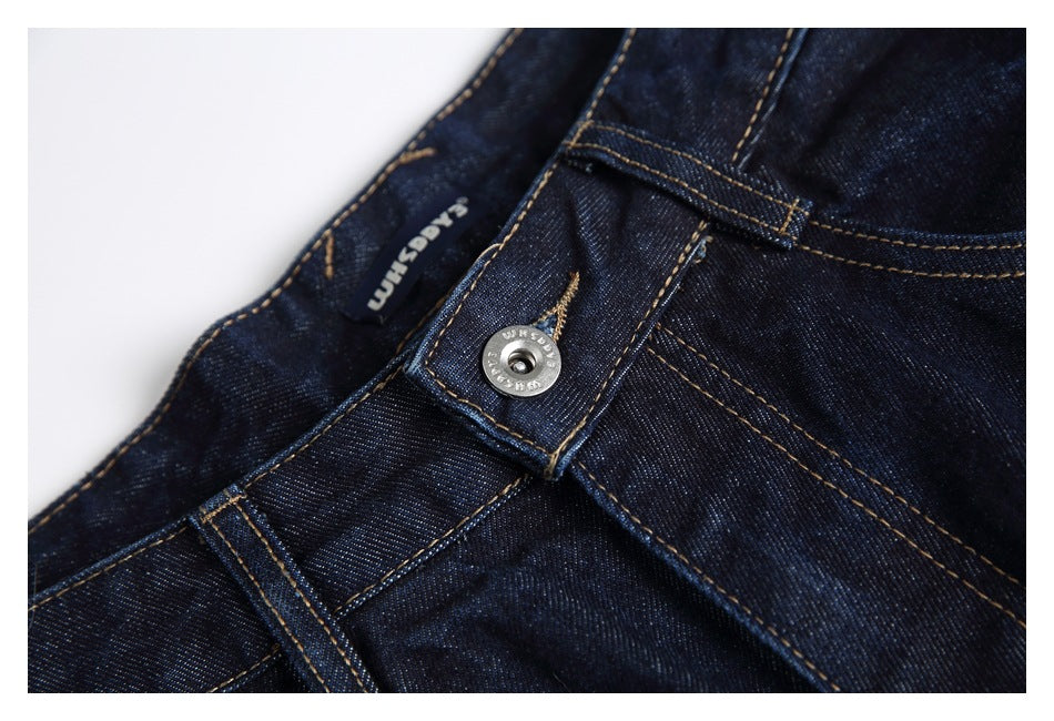 Close-up of the dark indigo jeans' waistband button, belt loop, inner label and contrast stitching.