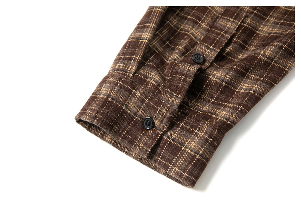 Close-up of a brown plaid shirt cuff with two dark buttons and a stitched edge.