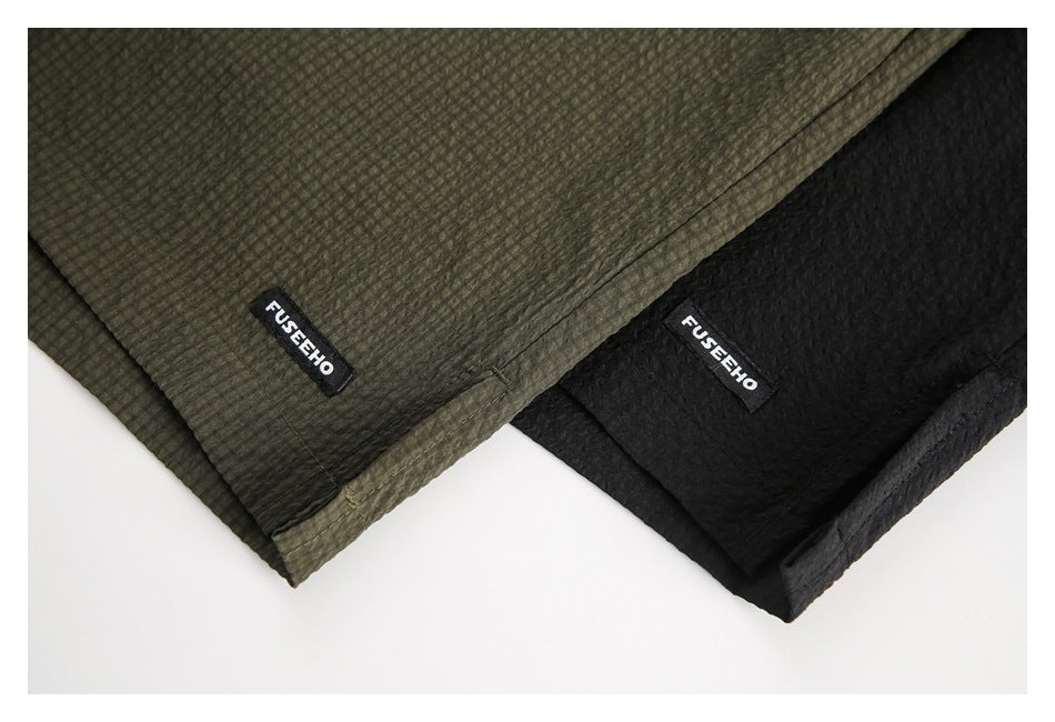 Close-up of olive and black shorts with small sewn FUSEEHO labels and textured fabric.