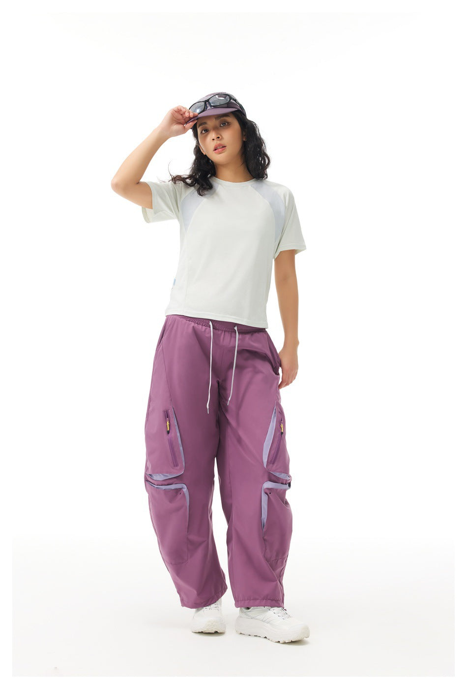 Full-length view of a model wearing plum-purple cargo pants with pale pocket trim and a white color-block shirt.