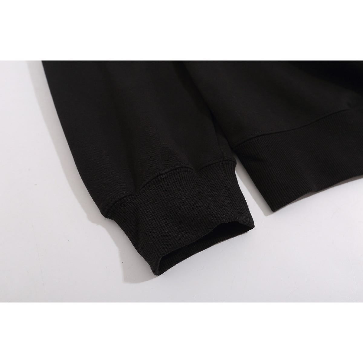 Close-up of the black sweatshirt's ribbed sleeve cuffs and stitched seams.