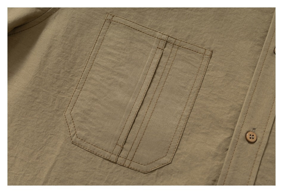 Close-up of a tan shirt's stitched chest pocket beside the button placket.
