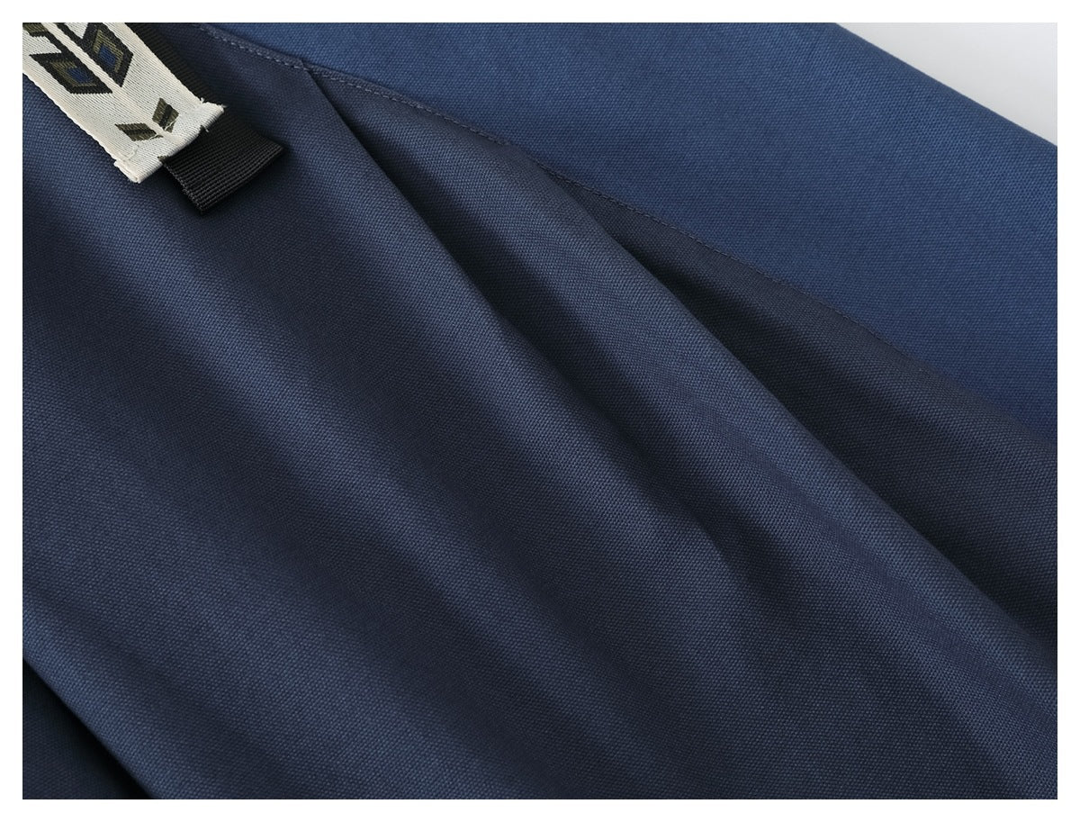 Close-up of blue trouser fabric and stitched seams, with part of the patterned belt visible.
