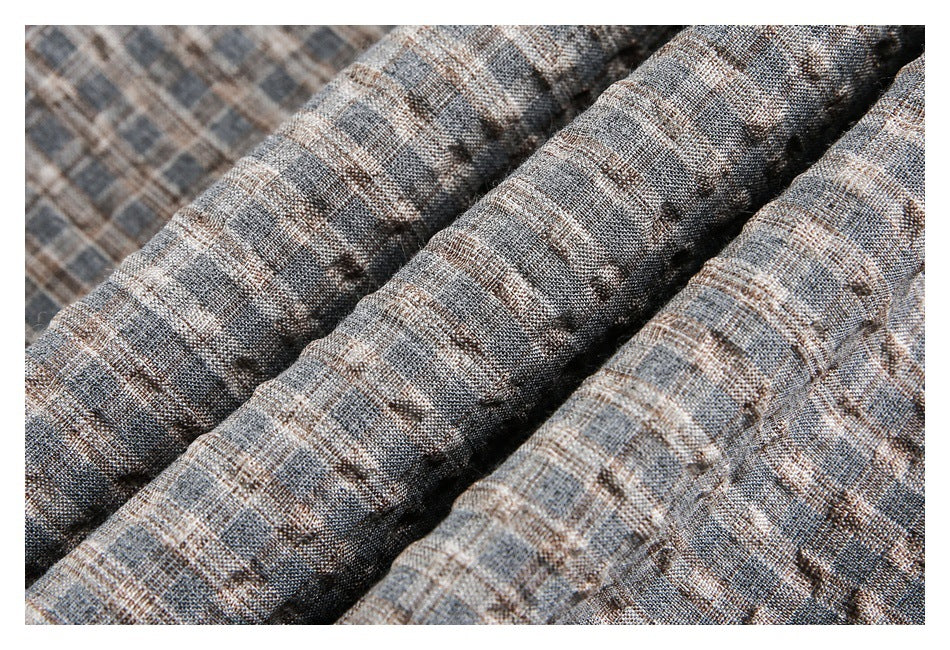 Close-up of gray-brown plaid fabric arranged in soft folds.