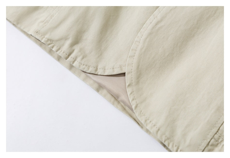 Close-up of the curved hem and side seam of a pale beige garment.