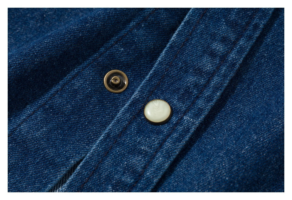 Close-up of two pale buttons on the placket of a blue denim shirt.